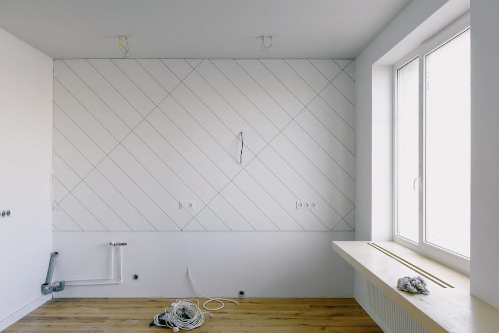 Mastering the First Impression: Your intriguing post title goes here Modern room with renovation materials including cables and wooden floor, bright daylight streaming through the window.